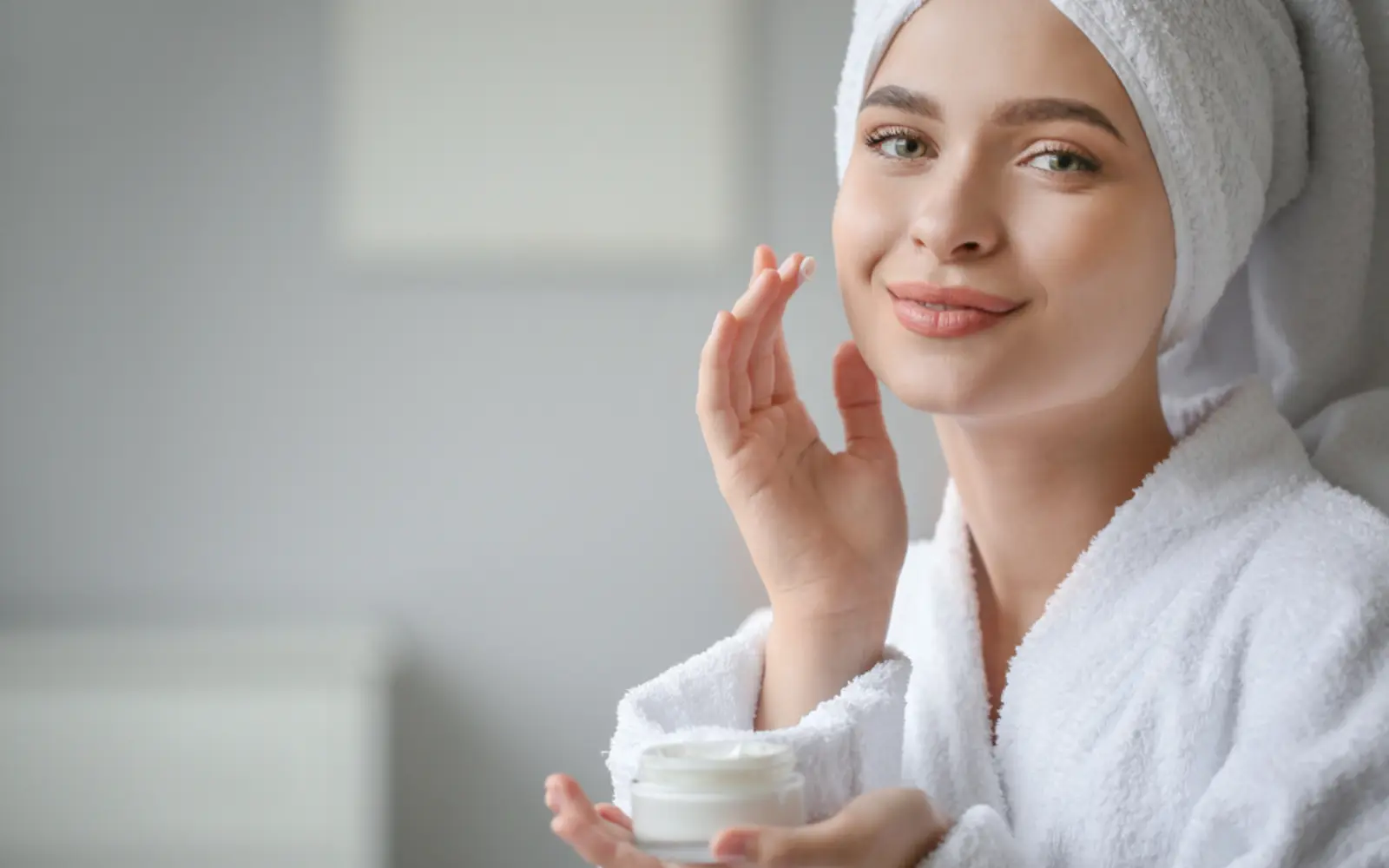 A guest in a robe applying skincare cream